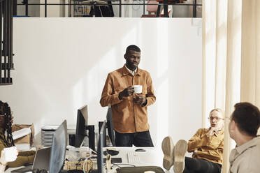 Male programmer discussing with colleagues at tech start-up office - MASF30840