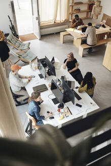 Blick von oben auf die Kollegen eines Startup-Unternehmens, die im Büro zusammenarbeiten - MASF30852