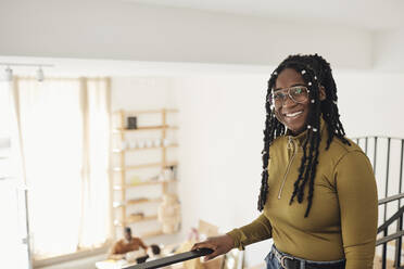 Portrait of smiling female computer programmer standing by railing at tech start-up office - MASF30859