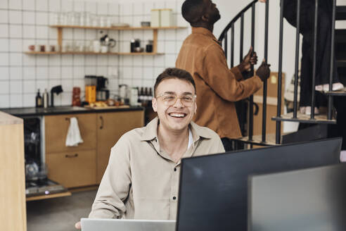 Porträt eines glücklichen männlichen Computerprogrammierers, der im Büro sitzt - MASF30886