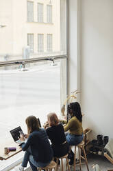 High angle view of female computer programmers working together while sitting in tech start-up office - MASF30889