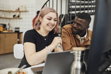 Männlicher Computerprogrammierer diskutiert mit Blick auf eine glückliche weibliche Kollegin im Büro eines Start-up-Unternehmens - MASF30922