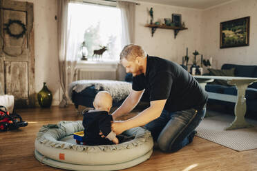 Vater trägt seinen Sohn in der Babyschale zu Hause - MASF31066