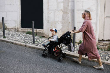 Mutter schiebt ihren Sohn im Kinderwagen über die Straße - MASF31096