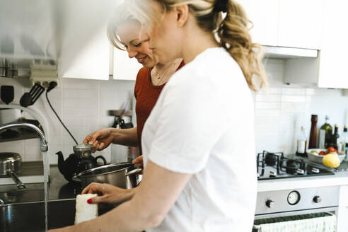 Frau macht Hausarbeit durch Freundin bereitet Tee in der Küche zu Hause - MASF31133