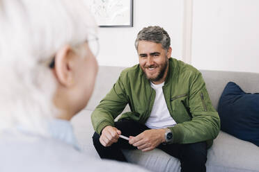 Lächelnder Mann im Gespräch mit einer Psychotherapeutin im Therapiebüro - MASF31139