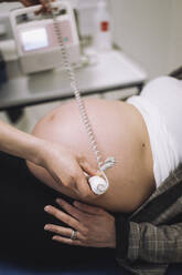 Hände einer Gynäkologin bei der Ultraschalluntersuchung des schwangeren Bauches einer Patientin in einer medizinischen Klinik - MASF31156