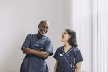 Glückliche Gesundheitsexperten, die sich gegenseitig an einer weißen Wand im Krankenhaus ansehen - MASF31216