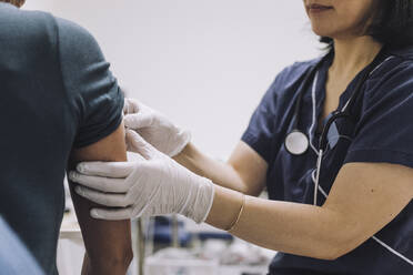 Mittelteil einer Gynäkologin mit Schutzhandschuhen bei der Untersuchung einer Patientin in einer medizinischen Klinik - MASF31223