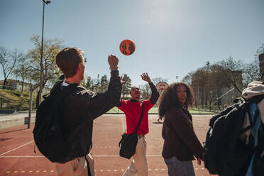 Männer spielen mit Ball, während sie mit Freunden auf einem Sportplatz an einem sonnigen Tag spazieren gehen - MASF31260