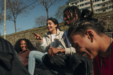 Happy woman gesturing while talking with multiracial friends on sunny day - MASF31269