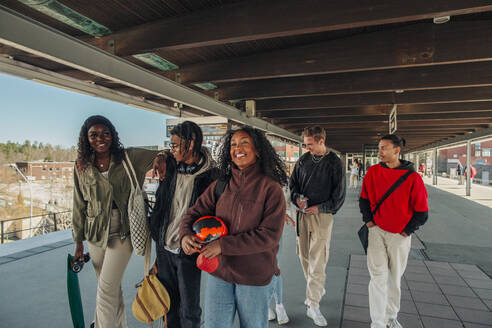 Männliche und weibliche Freunde verschiedener Rassen gehen zusammen unter einer Brücke am Bahnhof - MASF31285