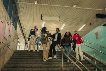 Männliche und weibliche Freunde, die sich auf den Stufen einer U-Bahn-Station vergnügen - MASF31296