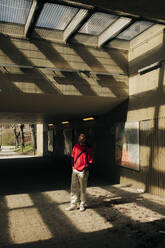 Junger Mann steht im Sonnenlicht unter einer Unterführung - MASF31327