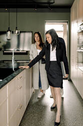 Immobilienmakler zeigt Ehepaar Kücheninsel zu Hause - MASF31382
