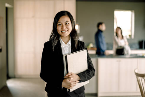 Portrait of saleswoman with folder standing at new home - MASF31396