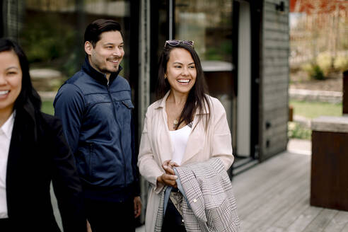 Ein glückliches Paar steht neben einer Verkäuferin vor einem Haus - MASF31399