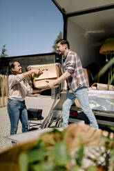 Couple unloading box from truck while relocating to new house - MASF31425