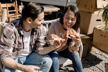 Fröhliches Paar beim Pizzaessen während des Umzugs in die neue Wohnung - MASF31437