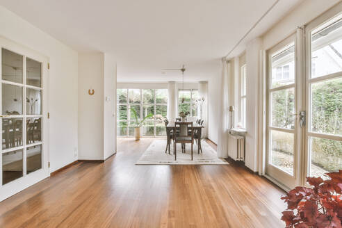 Dining table in dining area in living room of apartment with windows and glass doors leading to garden - ADSF35516