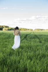 Frau mit Hut auf einem Feld stehend - LLUF00713