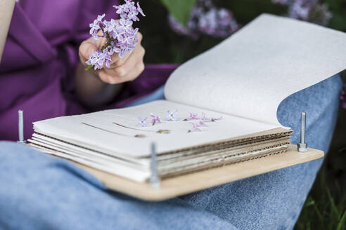 Frau mit Buch und fliederfarbenen Blumen - LLUF00720