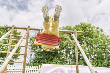 Girl swinging on swing at playground - KMKF01859