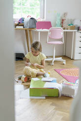 Girl doing craftwork sitting at home - KMKF01862