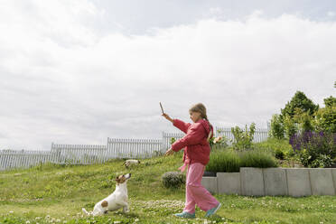 Mädchen spielt mit Hund im Garten - KMKF01865