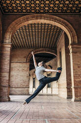 Ballet dancer dancing under historic arcades - JRVF02948
