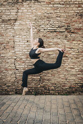 Ballet dancer dancing in front of brick wall - JRVF02961