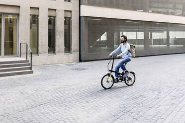 Lächelnder Mann auf dem Fahrrad in der Stadt - XLGF02971