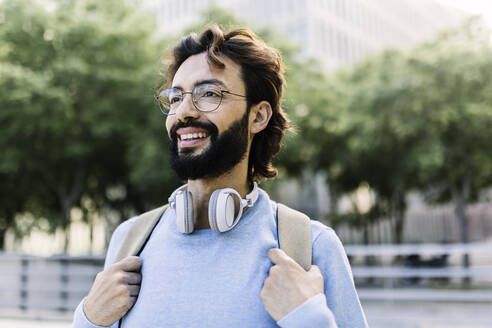 Lächelnder bärtiger Mann mit drahtlosen Kopfhörern - XLGF02982