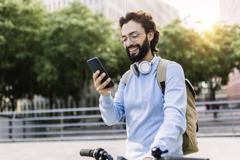 Glücklicher Mann mit Fahrrad und Mobiltelefon - XLGF02987