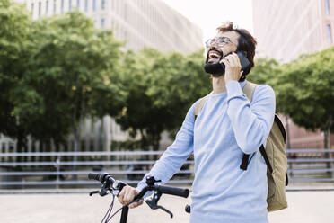 Glücklicher bärtiger Mann, der mit einem Mobiltelefon spricht - XLGF02989