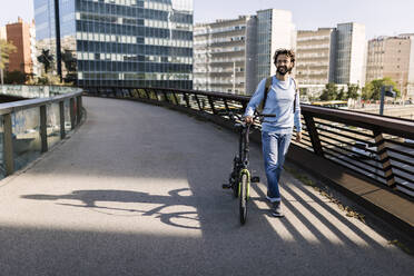 Lächelnder Mann mit Fahrrad auf einer Fußgängerbrücke - XLGF03008