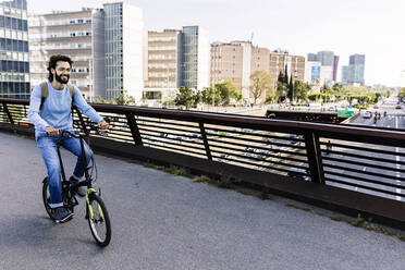 Smiling man riding bicycle on footbridge - XLGF03009