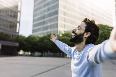 Happy man with arms outstretched in city - XLGF03013