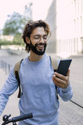 Smiling man with beard using phone - XLGF03015