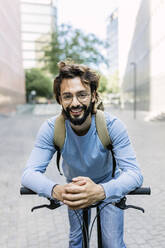 Lächelnder bärtiger Mann lehnt Fahrrad in der Stadt - XLGF03018