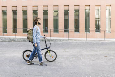 Man with bicycle walking on city street - XLGF03020