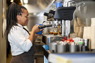 Lächelnder Barista beim Kaffeekochen in der Restaurantküche - DLTSF02988