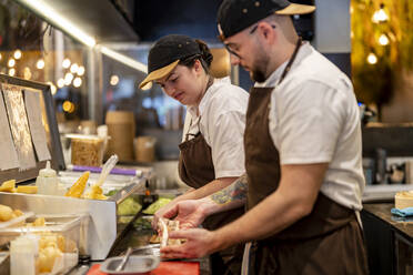 Koch bei der Zubereitung von Speisen durch einen Kollegen in der Restaurantküche - DLTSF02991