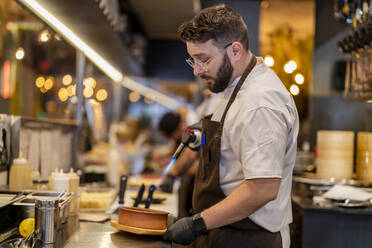 Koch mit Flammenfackel in der Restaurantküche - DLTSF02996