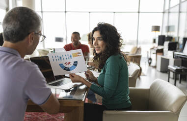 Happy businesswoman discussing chart with businessman - JCICF00157