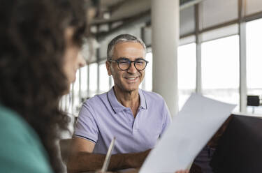 Glücklicher Geschäftsmann mit Brille bei der Arbeit im Büro - JCICF00158