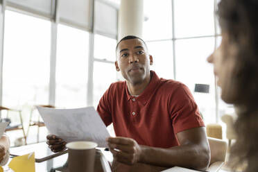 Smiling businessman with document looking at businesswoman - JCICF00172