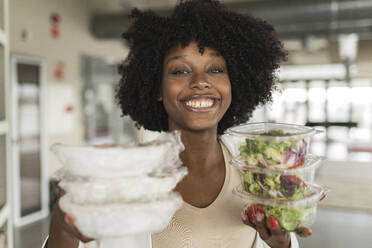 Glückliche Geschäftsfrau mit Salatcontainern im Büro - JCICF00174