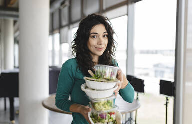 Smiling businesswoman with salad in office - JCICF00197
