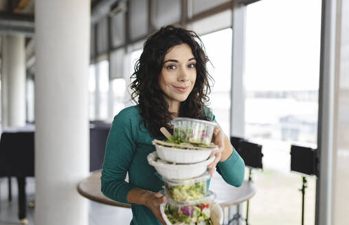 Lächelnde Geschäftsfrau mit Salat im Büro - JCICF00197